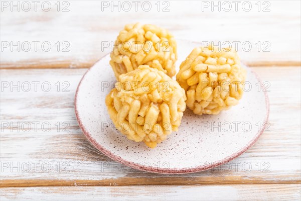 Traditional Tatar candy chak-chak made of dough and honey on a white wooden background. Side view, close up