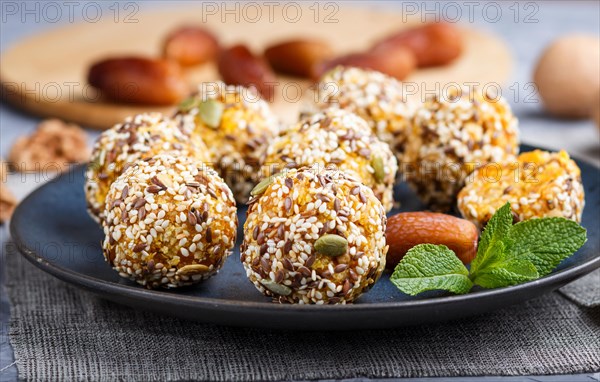 Energy ball cakes with dried apricots, sesame, linen, walnuts and dates with green mint leaves on a blue ceramic plate. side view, close up, macro, selective focus. vegan homemade candy