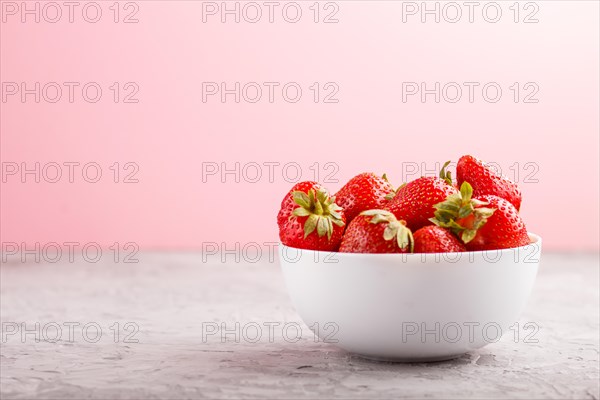 Fresh red strawberry in white bowl on gray and pink background. side view, close up, selective focus, copy space