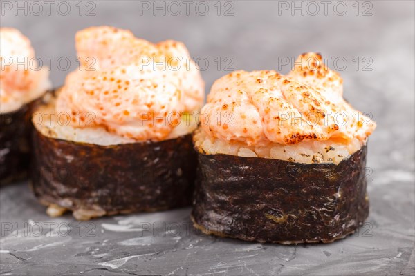Japanese maki sushi rolls with flying fish roe, cheese on black concrete background. Side view, close up, macro