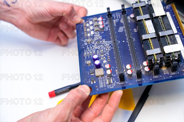 Close-up of the hands of a technician holding an electronic component of computer in a workshop