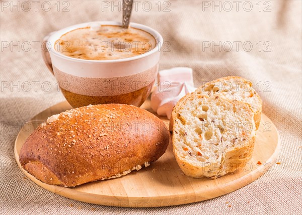 Sweet buns, meringues and coffee cup on a wooden board and linen tablecloth