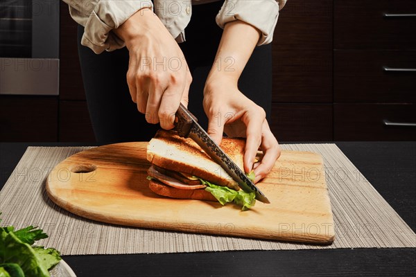Unrecognizable woman cuts on half homemade club sandwich