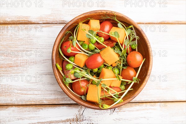 Vegetarian vegetable salad of tomatoes, pumpkin, microgreen pea sprouts on white wooden background. Top view, flat lay, copy space