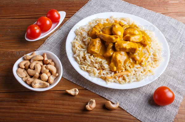 Rice with chicken curry sauce with cashew on brown wooden background. close up