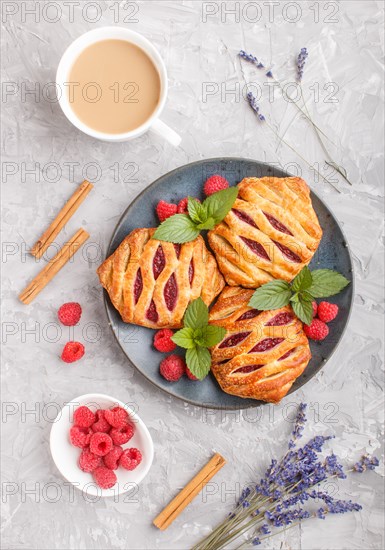 Puff pastry buns with strawberry jam on blue ceramic plate on gray concrete background, cup of coffee, lavender, cinnamon, mint leaves. top view, flat lay, close up