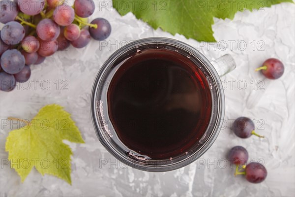 Glass of red grape juice on a gray concrete background. Morninig, spring, healthy drink concept. Top view, close up, flat lay