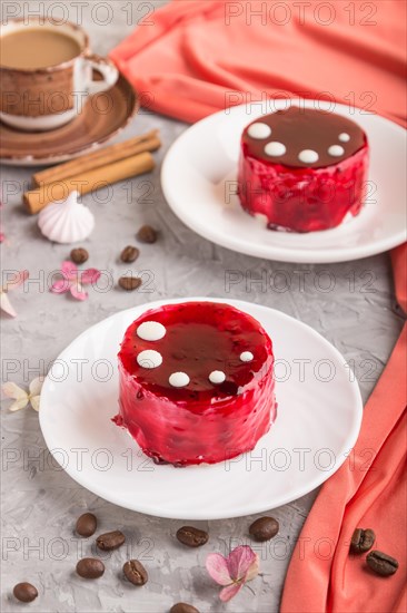 Red cake with souffle cream with cup of coffee on a gray concrete background and red textile. side view, close up, selective focus