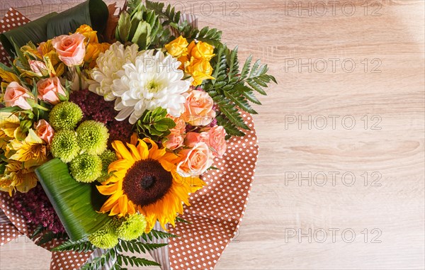 Bouquet of alstroemeria, sunflower, roses, chrysanthemum on a wooden background. floristic composition