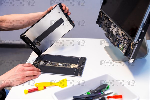 Side view cropped photo of a male technician fixing a digital tablet in a workshop