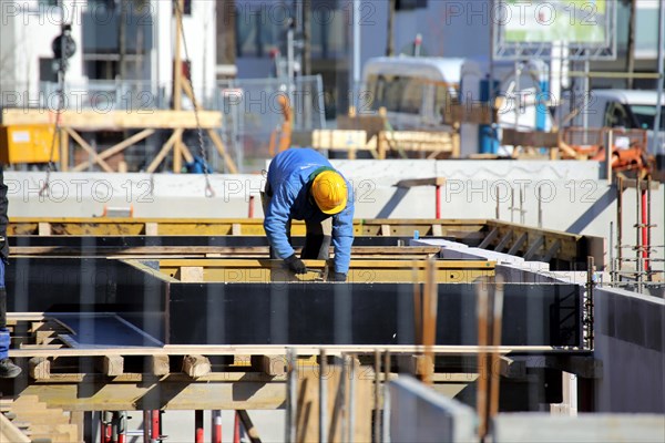 Construction work on the foundations of a large apartment building. The construction workers are wearing construction helmets in accordance with regulations