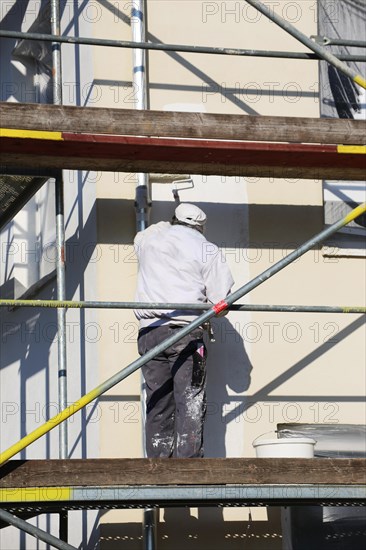Painter painting the facade of a new residential building (Mutterstadt development area, Rhineland-Palatinate)