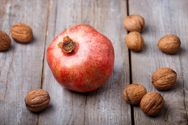 Ripe garnet with walnuts on a rustic wooden background