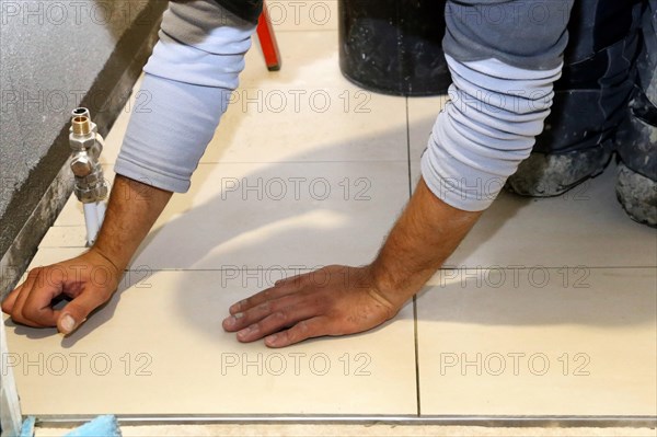 Tiler lays modern large floor tiles in a bathroom