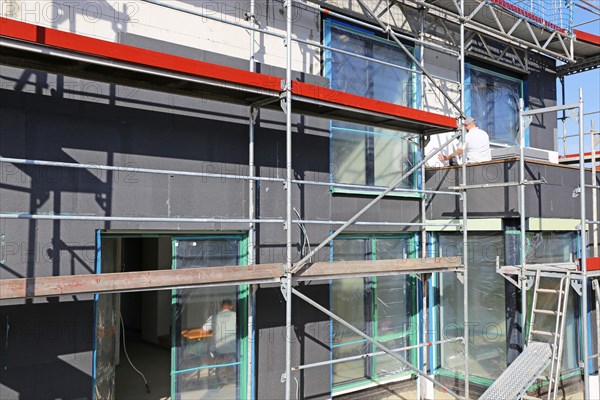 Construction workers insulate a house facade