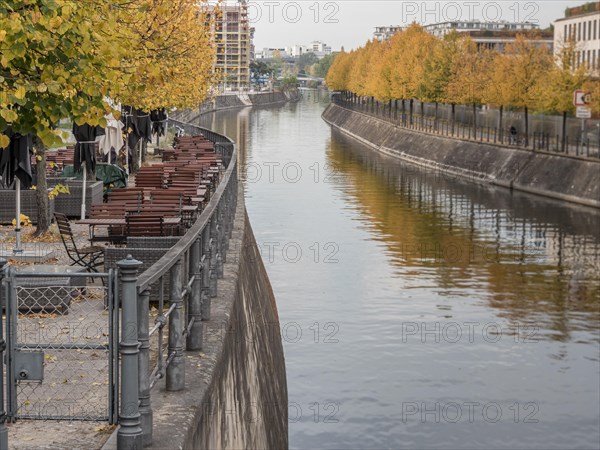 An autumnal scene by a quiet river with an empty cafe on the bank in an urban setting Allee Spree Berlin