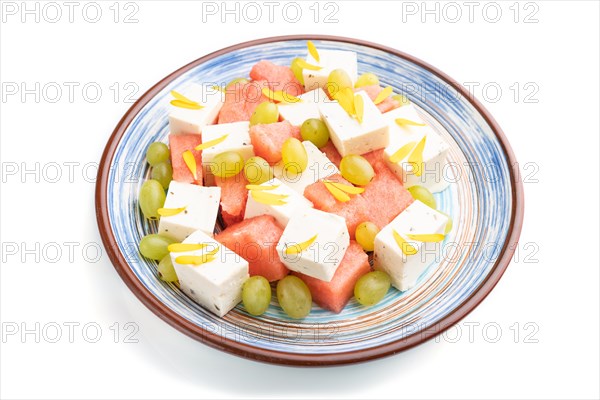 Vegetarian salad with watermelon, feta cheese, and grapes on blue ceramic plate isolated on white background. Side view, close up