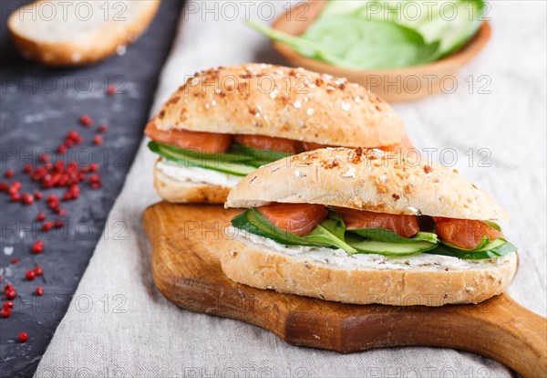 Smoked salmon sandwiches with cucumber and spinach on wooden board on a linen background. side view, close up