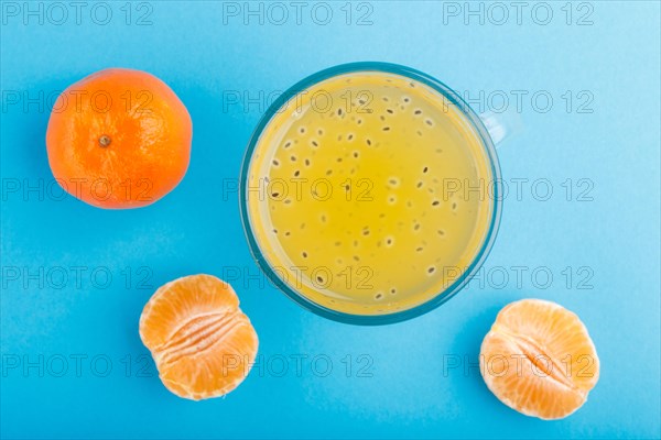 Glass of tangerine orange colored drink with basil seeds on a blue background. Morninig, spring, healthy drink concept. Top view, close up, flat lay