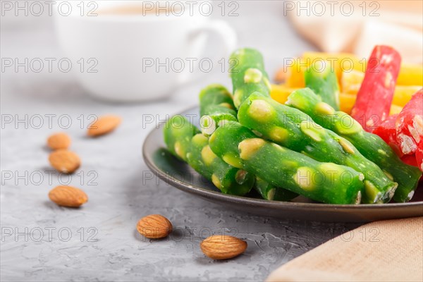 Set of various traditional turkish delight (rahat lokum) in blue ceramic plate with cup of coffee on a gray concrete background. side view, close up, selective focus