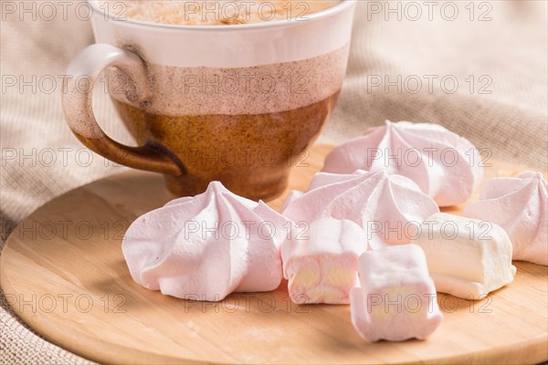 Sweet buns, meringues and coffee cup on a wooden board and linen tablecloth