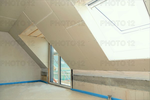 Attic conversion, loft conversion. You can see the pitched roof with door and skylight panelled with plasterboard