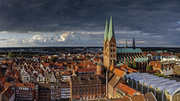 Panorama of a historic city with church towers and roofs under a dramatic evening sky, view from the tower of a church to the old town of Luebeck in the evening light