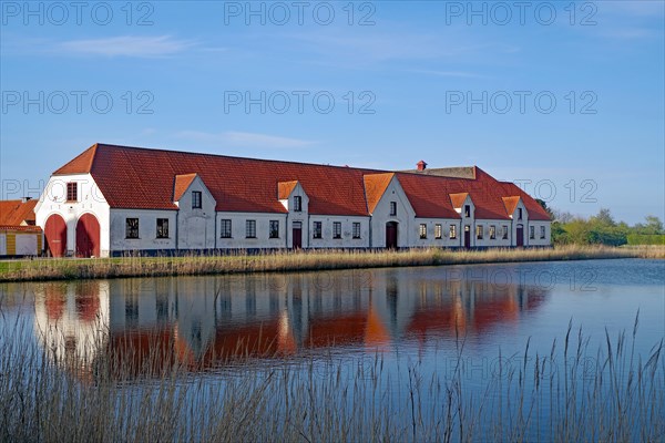 Large houses and the teahouse at Valdemars Slot are reflected in the calm water, Valdemars Slot, Manor Route, Tasinge, Denmark, Europe