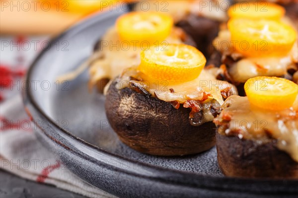 Stuffed fried champignons with cheese, kumquats and green peas on a gray concrete background. ceramic plate, side view, close up, selective focus