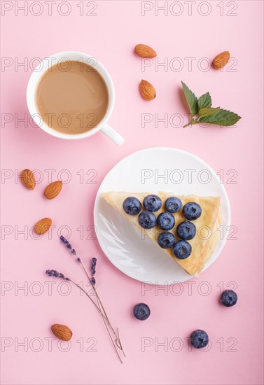 Homemade layered Napoleon cake with milk cream. Decorated with blueberry, almonds, mint on a pastel pink background and a cup of coffee. top view. flat lay, close up
