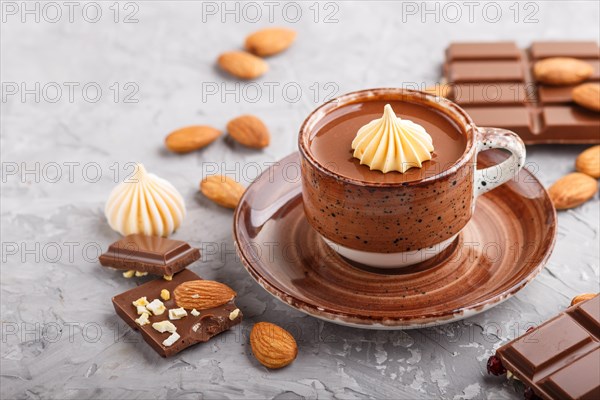 Cup of hot chocolate and pieces of milk chocolate with almonds on a gray concrete background. side view, close up, selective focus