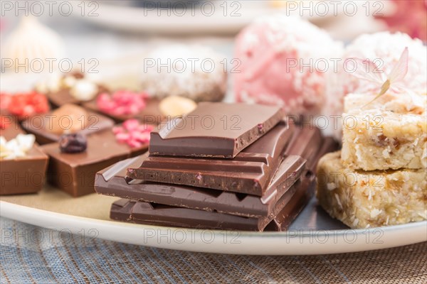 A pieces of homemade chocolate with coconut candies on a blue and brown textile. side view, close up, selective focus