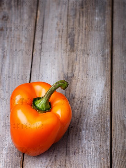 Fresh orange pepper on a rustic wooden background