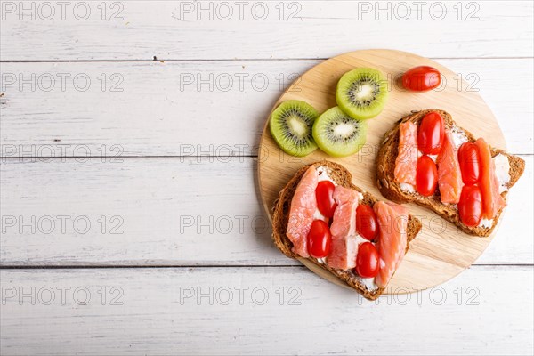 Smoked salmon sandwiches with butter and cherry tomatoes on white wooden background. top view, copy space