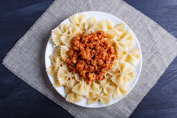 Farfalle bolognese pasta with minced meat on black wooden background. top view, close up