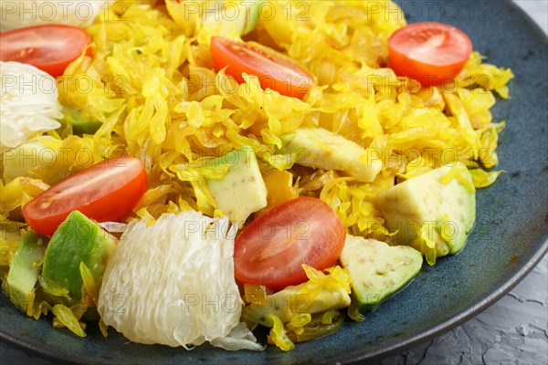 Fried pomelo with tomatoes and avocado on gray concrete background, close up, myanmar food