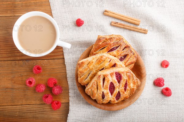Puff pastry buns with strawberry jam on wooden background with linen textile and a cup of coffee. top view, flat lay, close up
