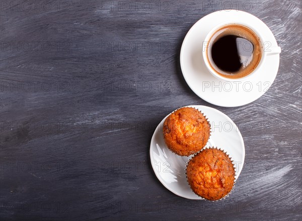 Two carrot muffins with cup of coffee on white plate on black wooden background. top view with copyspace