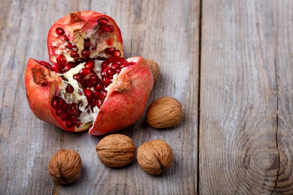 Ripe garnet with walnuts on a rustic wooden background