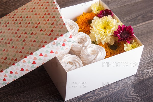 White box with white homemade zephyr and sunflowers and chrysanthemums on gray wooden background