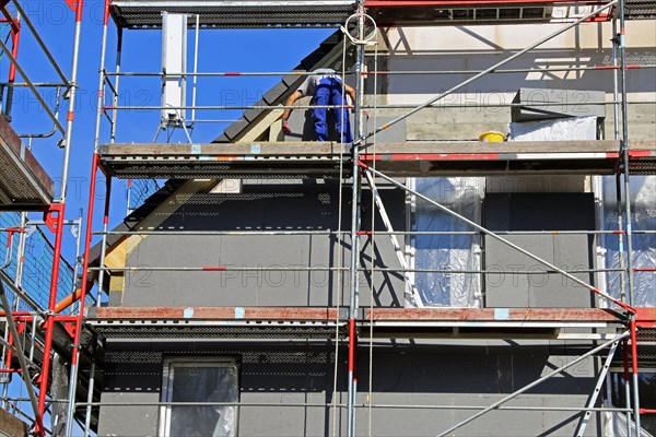 Construction workers insulate a house facade