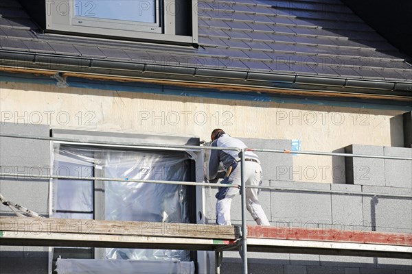 Construction workers insulate a house facade