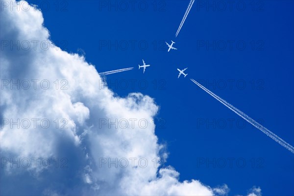Three passenger airplanes with contrails on a collision course