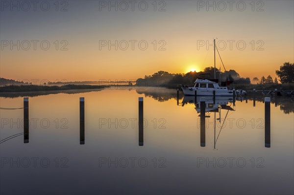 Sunrise in Prerow harbour with boats and a reflection in the water