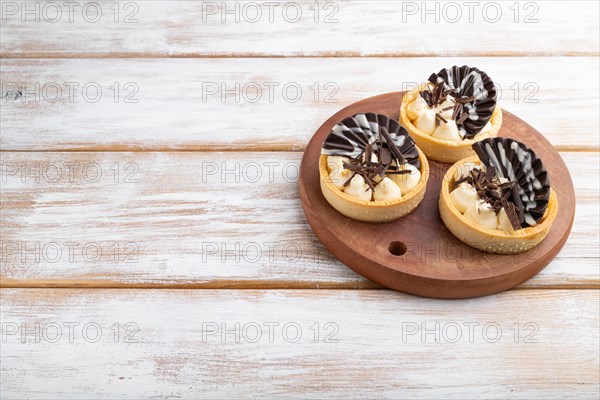 Sweet tartlets with chocolate and cheese cream on a white wooden background. side view, close up, copy space