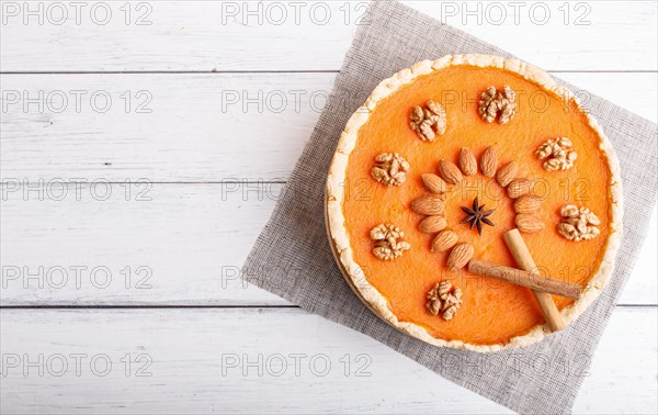 Traditional american sweet pumpkin pie decorated with nuts, on white wooden background. top view, copy space