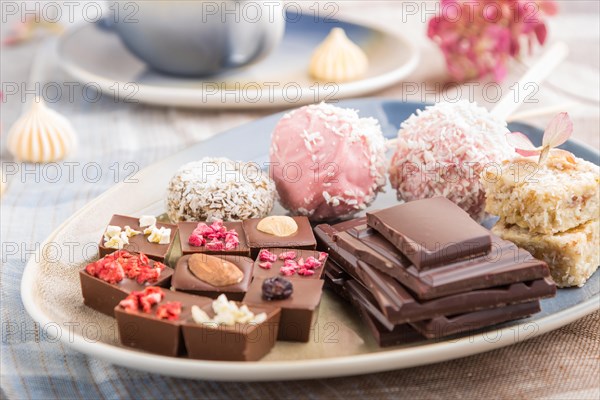 A pieces of homemade chocolate with coconut candies on a blue and brown textile. side view, close up, selective focus