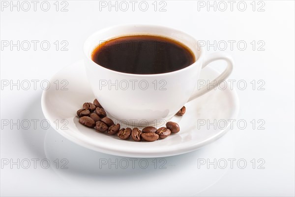 A cup of coffee with coffee beans on a plate, isolated on white, closeup