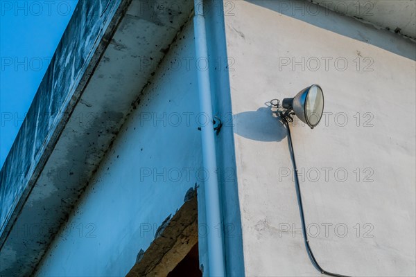 Flood light mounted on outside wall of abandoned concrete building with blue sky in background in South Korea
