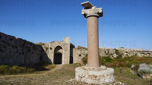 Old antique column in front of ruins with archway and blue sky in the background, sea fortress Methoni, Peloponnese, Greece, Europe